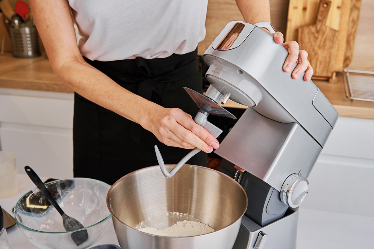 Femme cuisinant à la préparation des aliments, à l'aide d'un robot culinaire,