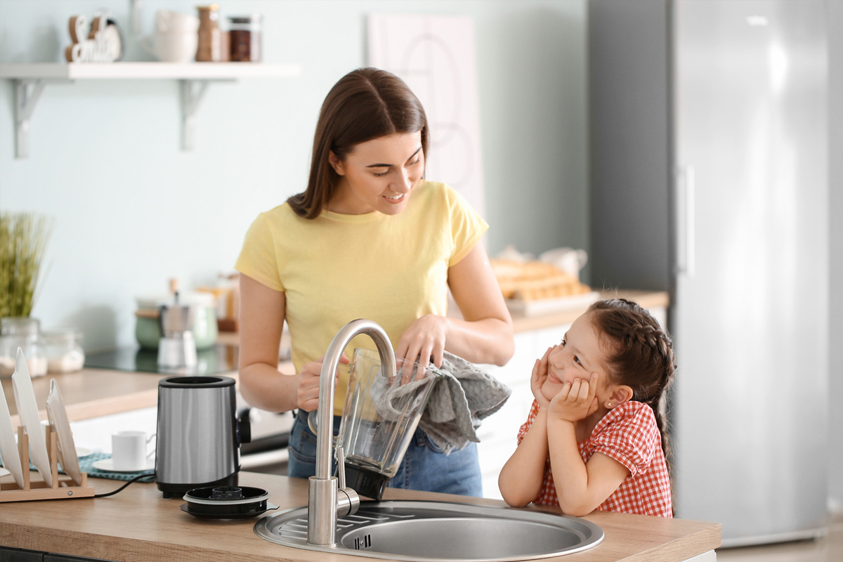 Mère et petite fille nettoyant le mélangeur dans la cuisine