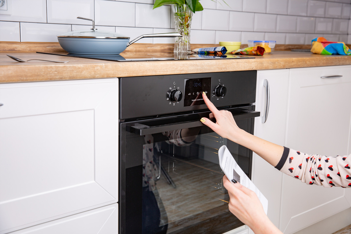 Femme réglant le mode de cuisson sur le panneau du four